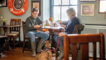 Un interior de madera con una mesa redonda, sillas y un perro con correa.