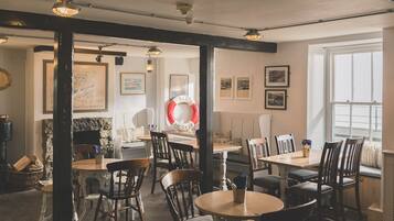 Un restaurante acogedor con muebles de madera, paredes de piedra y cuadros enmarcados.