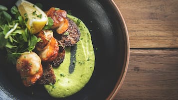 Un plato de comida con salsa verde, vegetales y rodajas de limón.