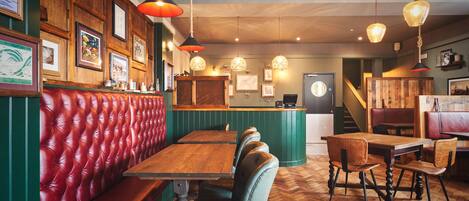 A restaurant interior with wooden tables, leather booths, and hanging pendant lights.
