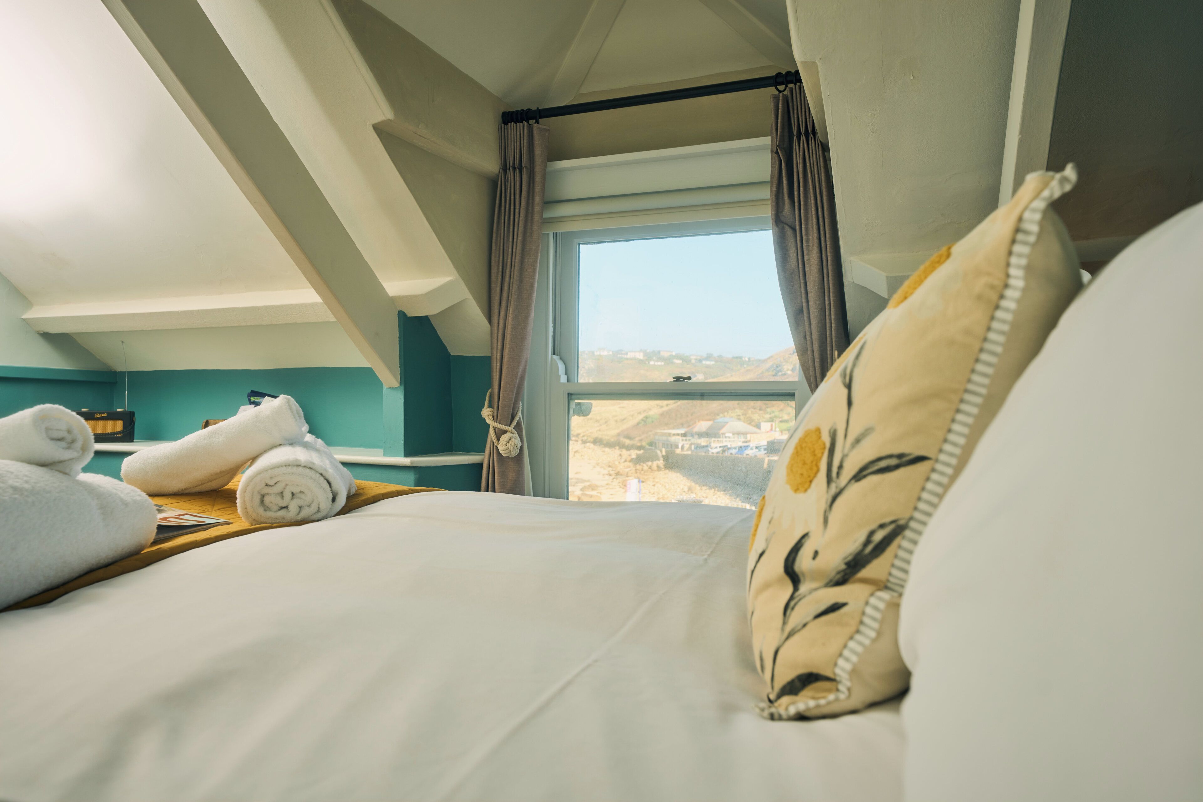 Habitació d'hotel amb un llit, una finestra amb cortines i vistes al paisatge.