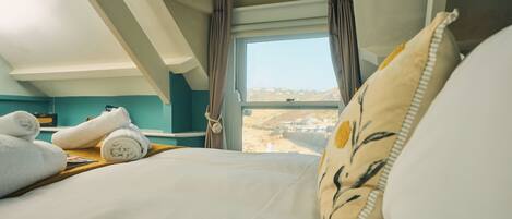 Une chambre d’hôtel avec un lit, une fenêtre avec des rideaux et une vue sur le paysage.
