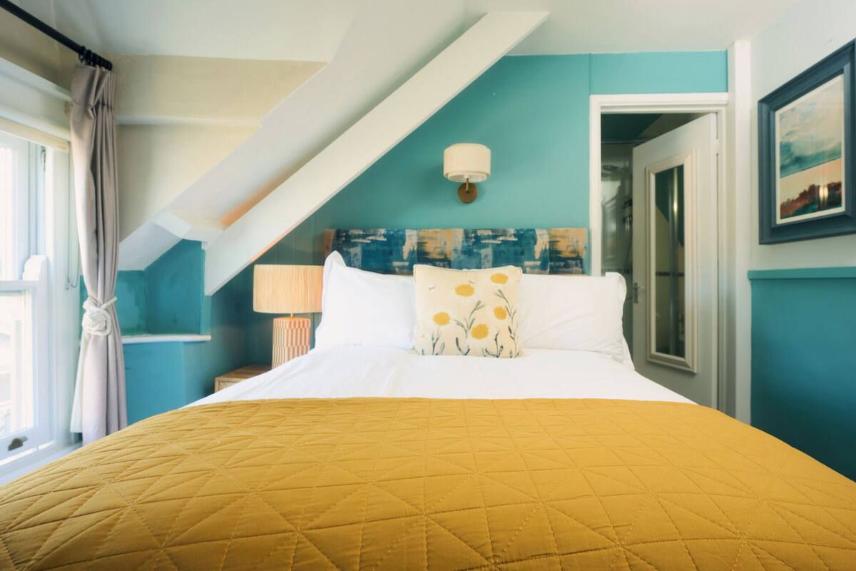 A bedroom with a bed, a nightstand, a lamp, and a painting on the wall.