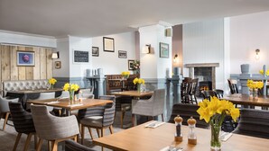 A restaurant with wooden tables, wicker chairs, and yellow flowers. - Rashleigh Arms (St Austell)