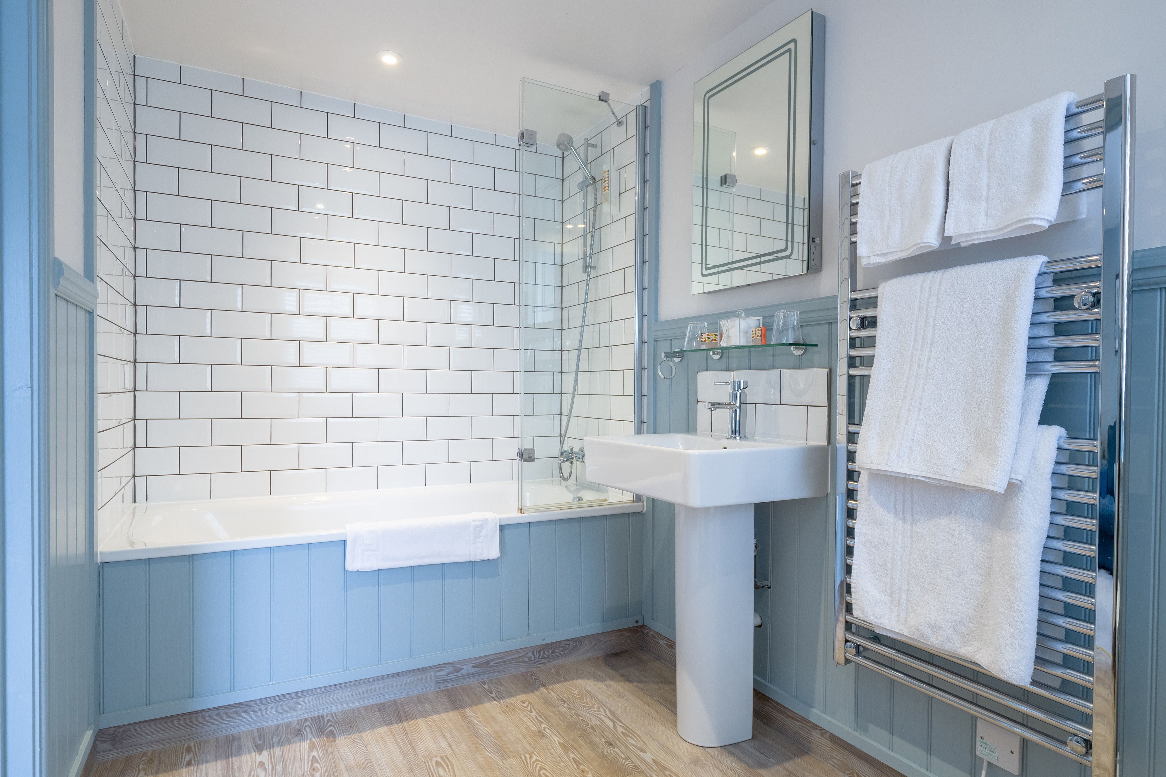 A modern bathroom with a glass-enclosed shower, a white bathtub, and a built-in sink.
