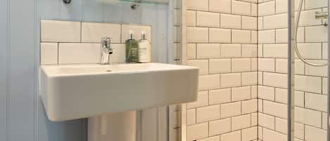 A bathroom with a white sink, a glass shower enclosure, and a tiled shower wall.