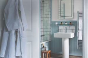A bathroom with a white sink, a mirror, and a tiled shower enclosure.
