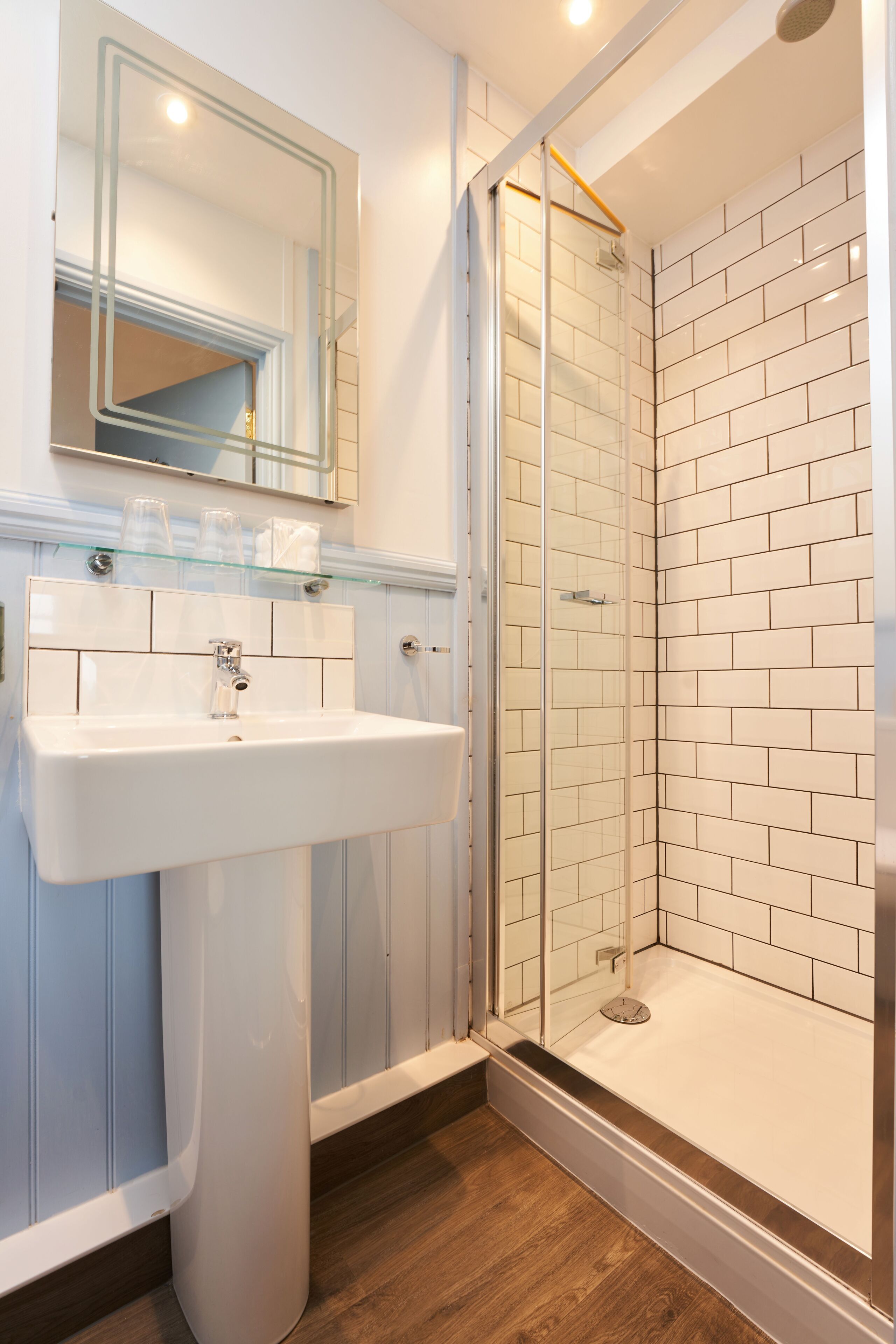 A bathroom with a glass-enclosed shower, a white sink, and a mirror above it.