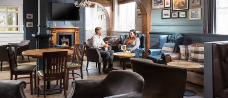 A cozy lounge area with leather seating, a fireplace, and a television.