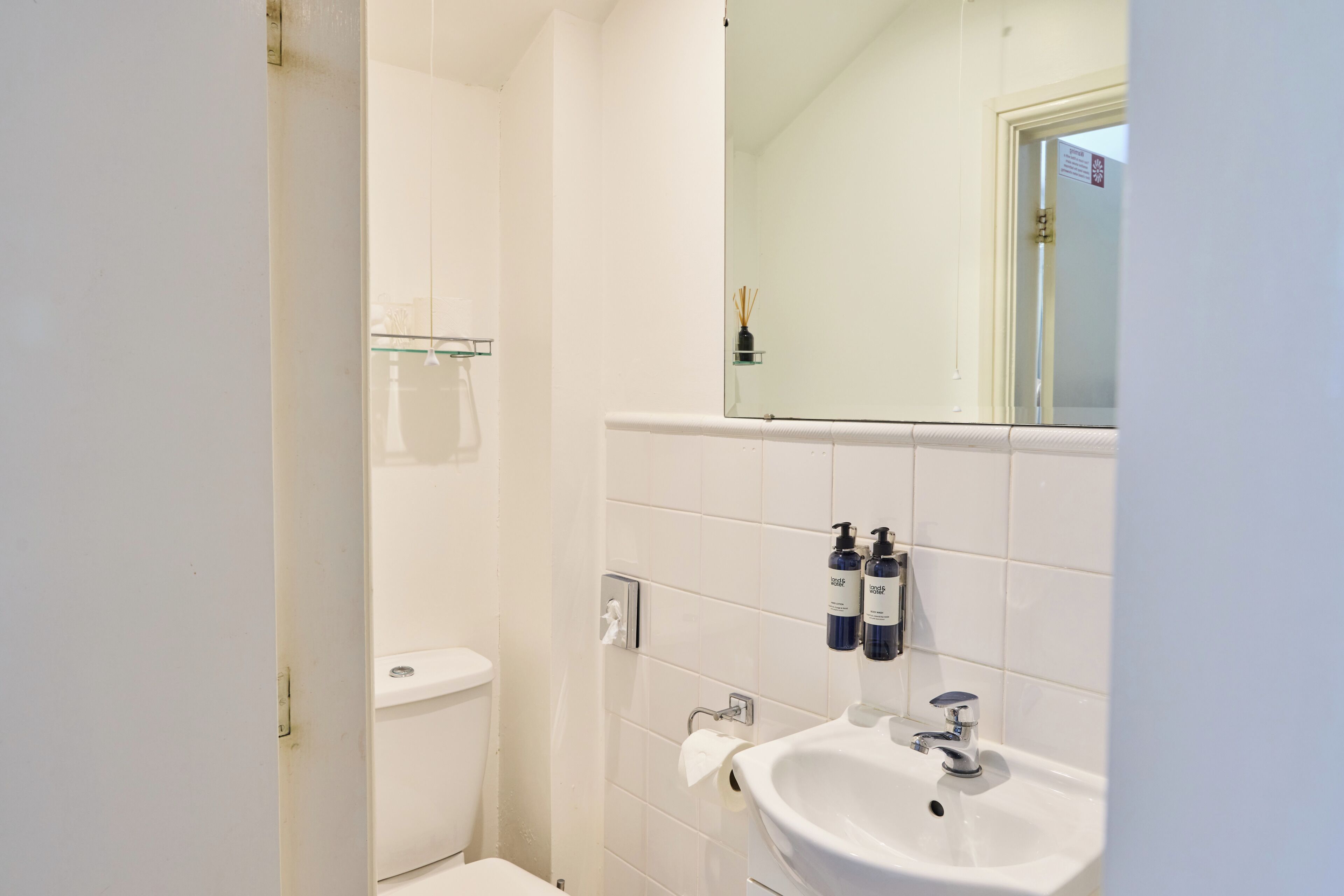 A bathroom with a white sink, a mirror, and two bottles of hand soap.