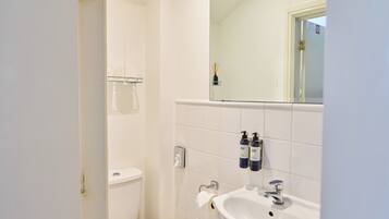 A bathroom with a white sink, a mirror, and two bottles of hand soap.