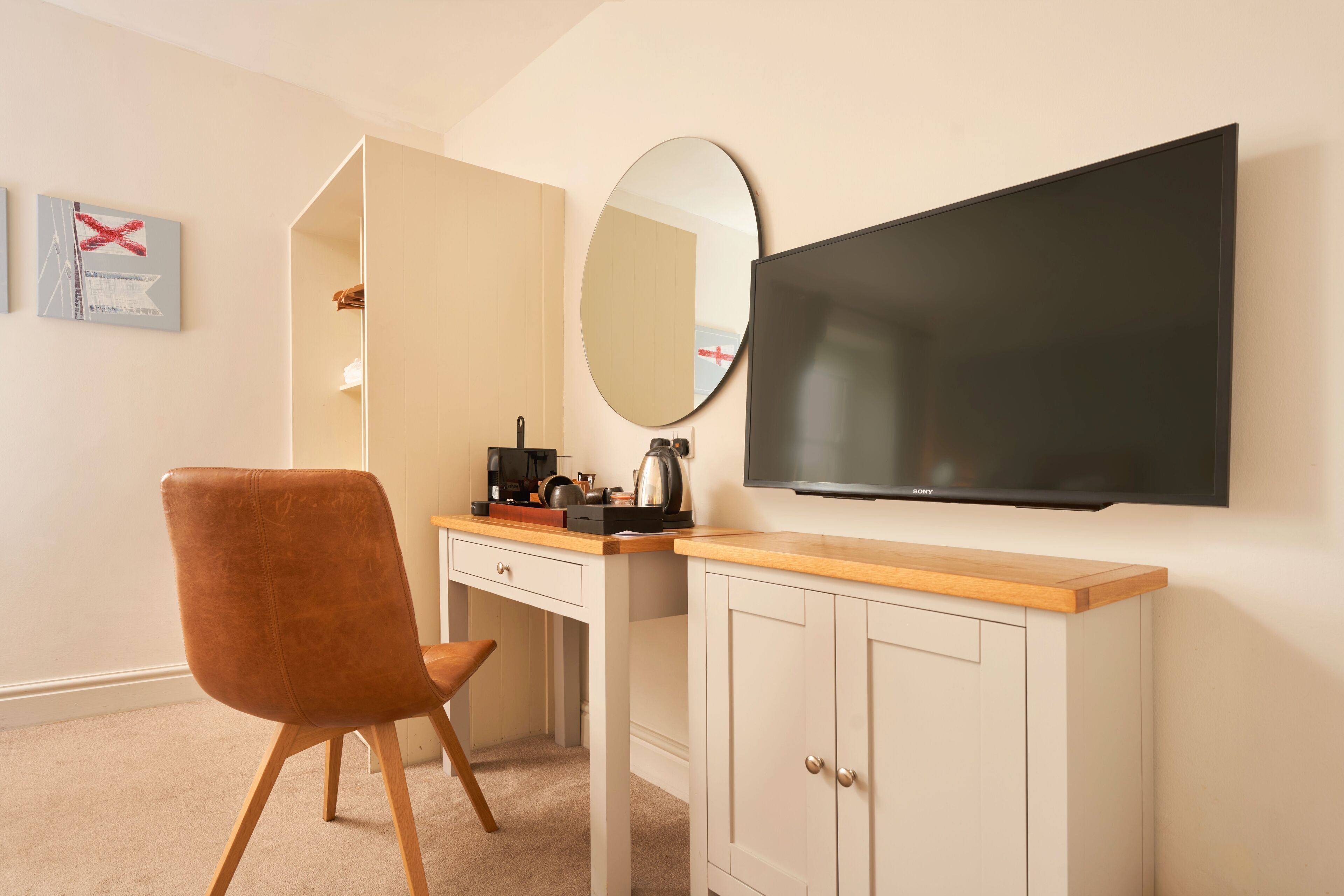 A bedroom with a bed, a desk with a chair, a TV, and a mirror.