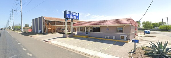 A motel with a red roof, a blue sign, and a parking lot. - Executive Inn and Suites (Port Isabel)