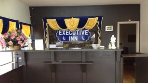 A reception desk with a sign reading "EXECUTIVE INN" and a decorative blue and yellow drape. - Executive Inn and Suites (Port Isabel)
