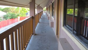 A corridor with a wooden railing, large windows, and a concrete floor. - Executive Inn and Suites (Port Isabel)