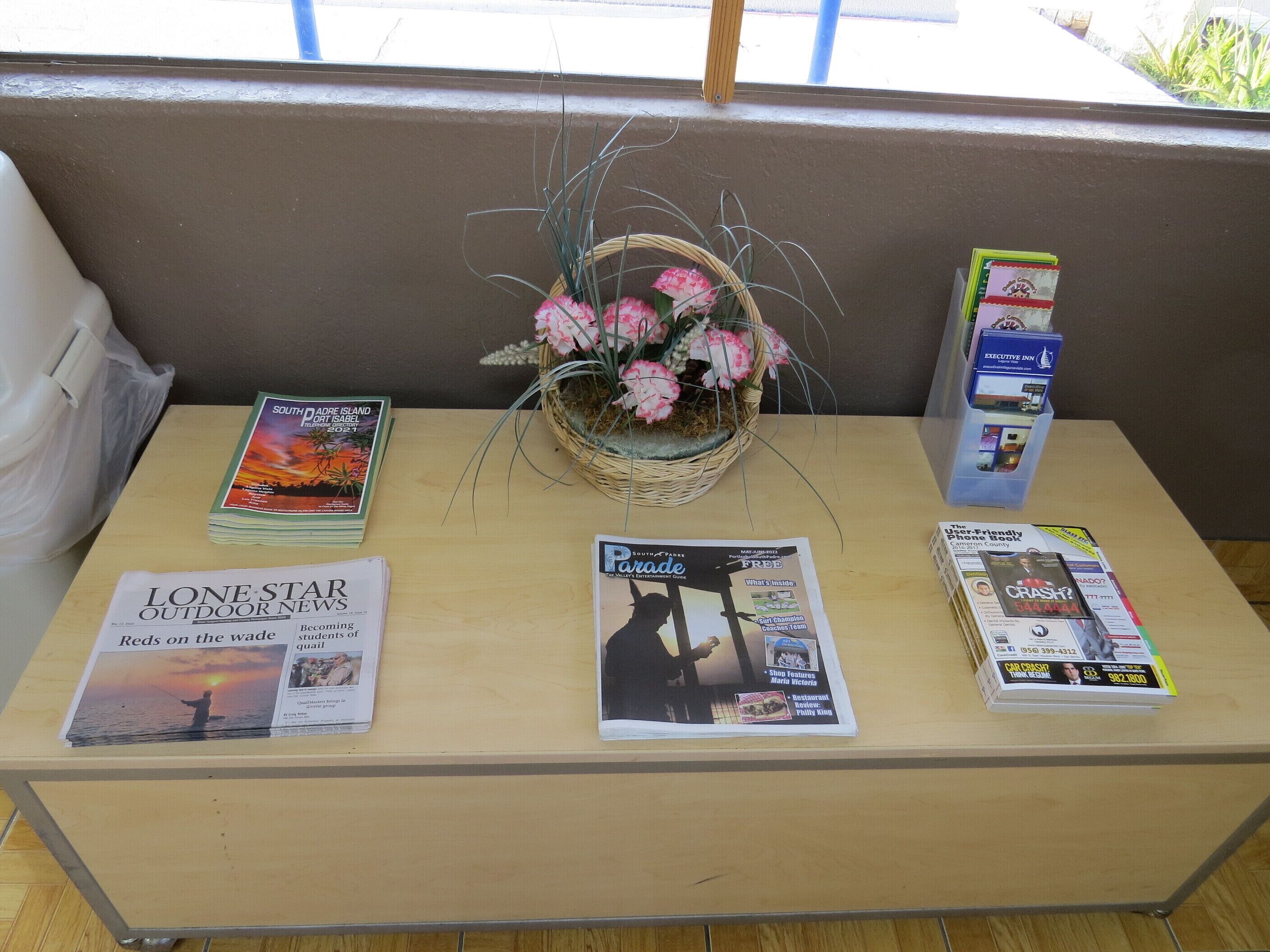 Une table avec des magazines, un panier de fleurs et un annuaire téléphonique.