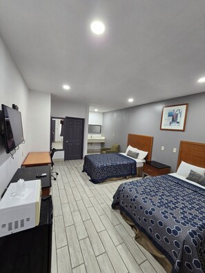 A hotel room with two beds, a desk, a TV, and a bathroom visible through an open door. - Executive Inn and Suites (Port Isabel)