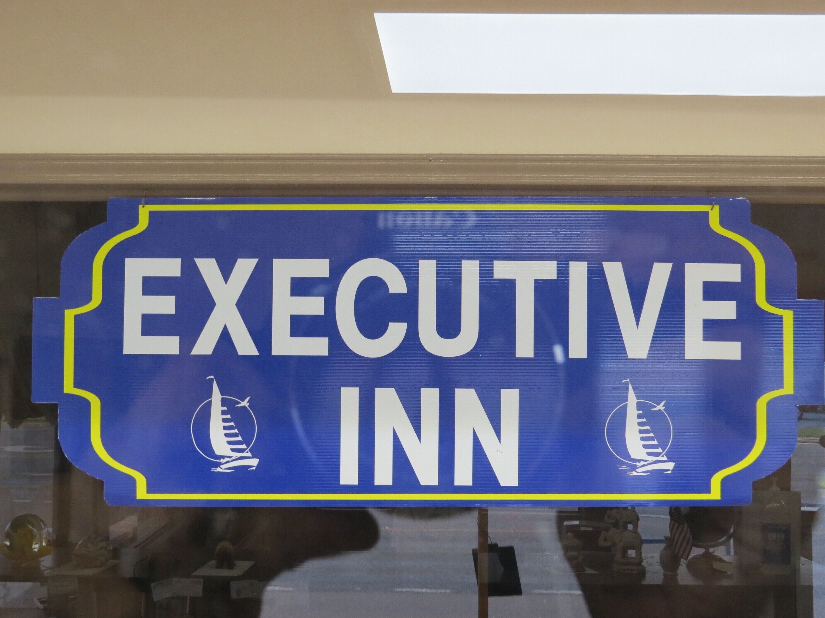 Um letreiro com as palavras 'EXECUTIVE INN' e dois ícones de saveiros.