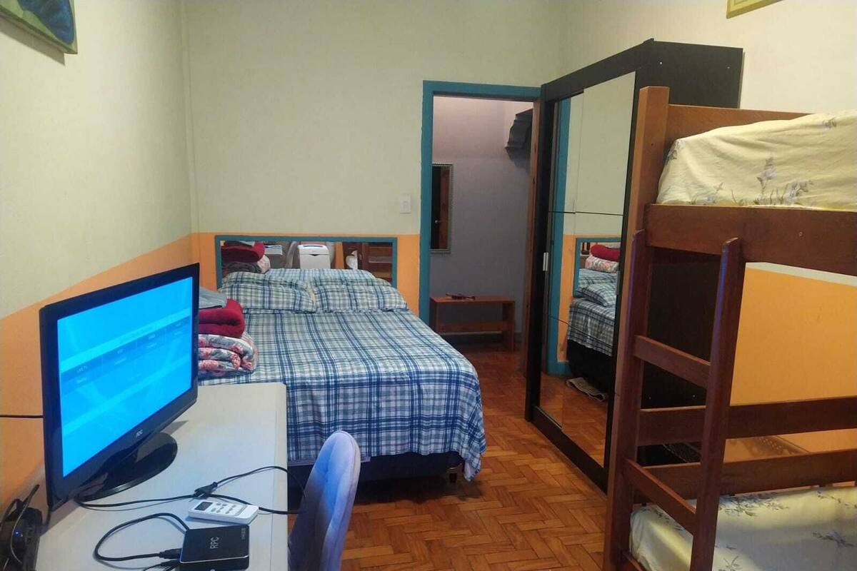 A room with a bunk bed, a desk with a computer, and a chair.