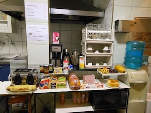 Uma cozinha com micro-ondas, torradeira e diversos alimentos sobre o balcão.