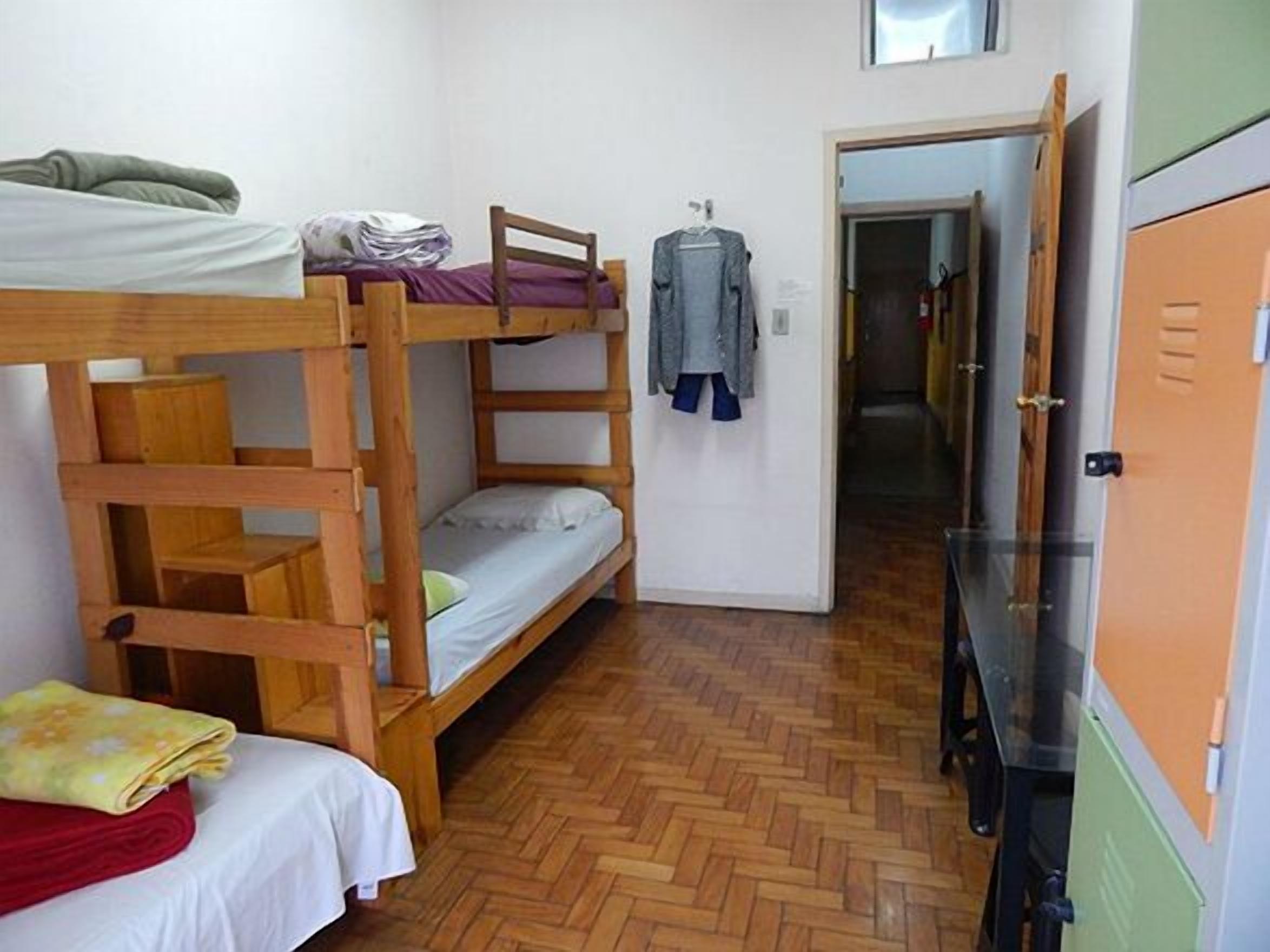Une chambre de dortoir avec des lits superposés, un petit bureau, une chaise et une armoire.
