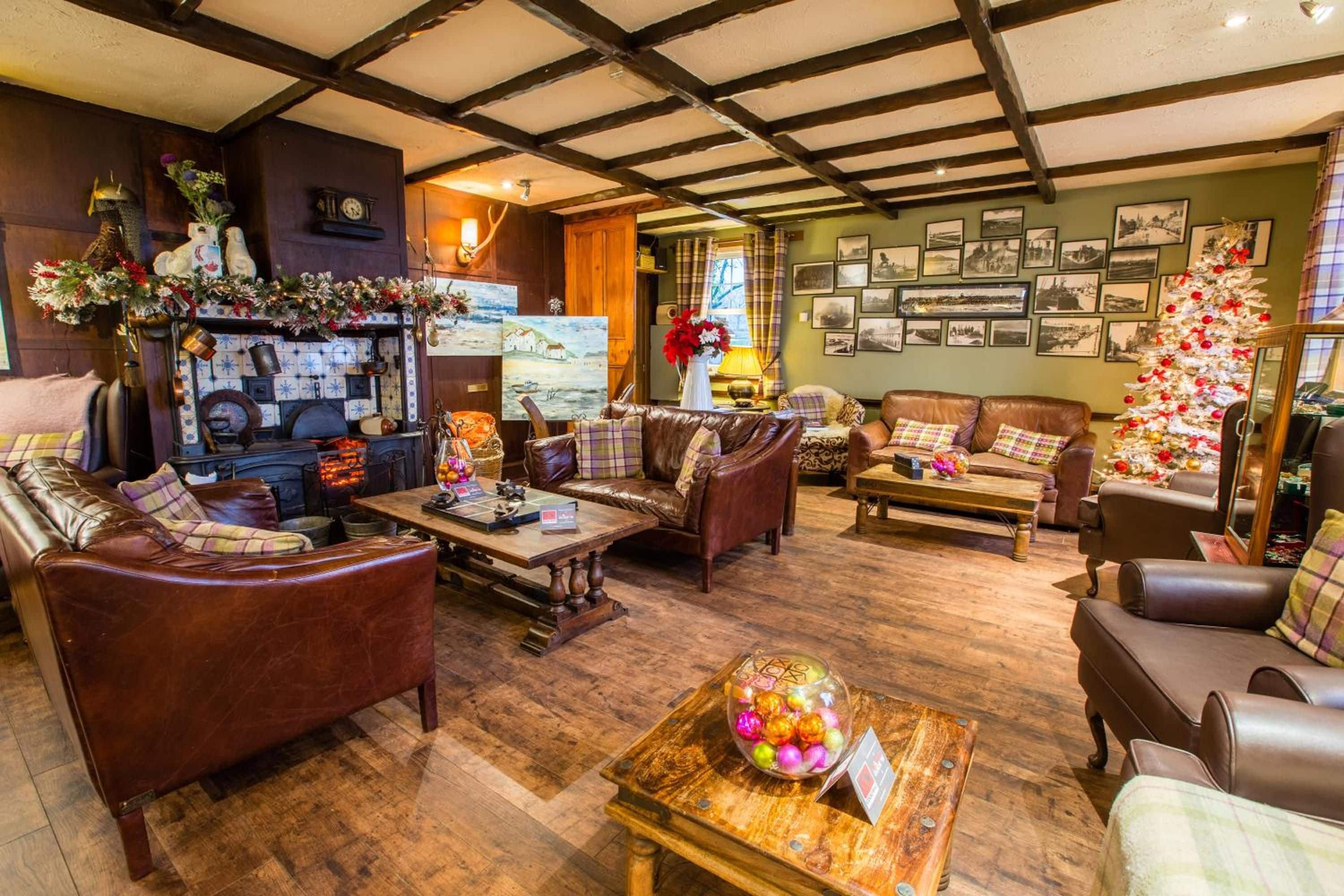 A cozy living room with leather sofas, a wooden coffee table, and a decorated Christmas tree.