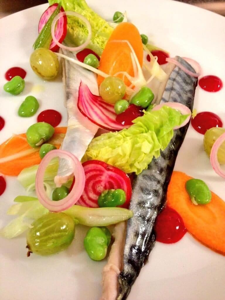 A plate of food with a variety of vegetables and a fish.