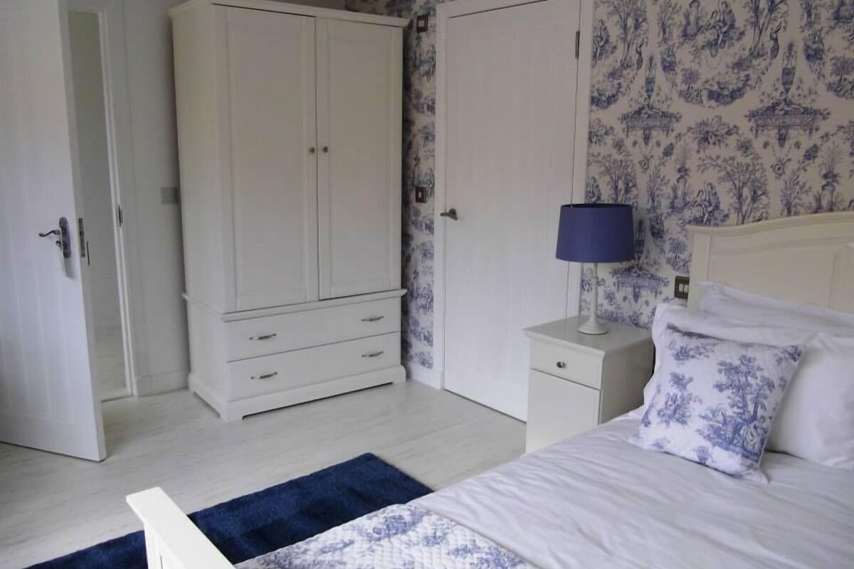 Ein Schlafzimmer mit Bett, Nachttisch, Kleiderschrank und Tür.