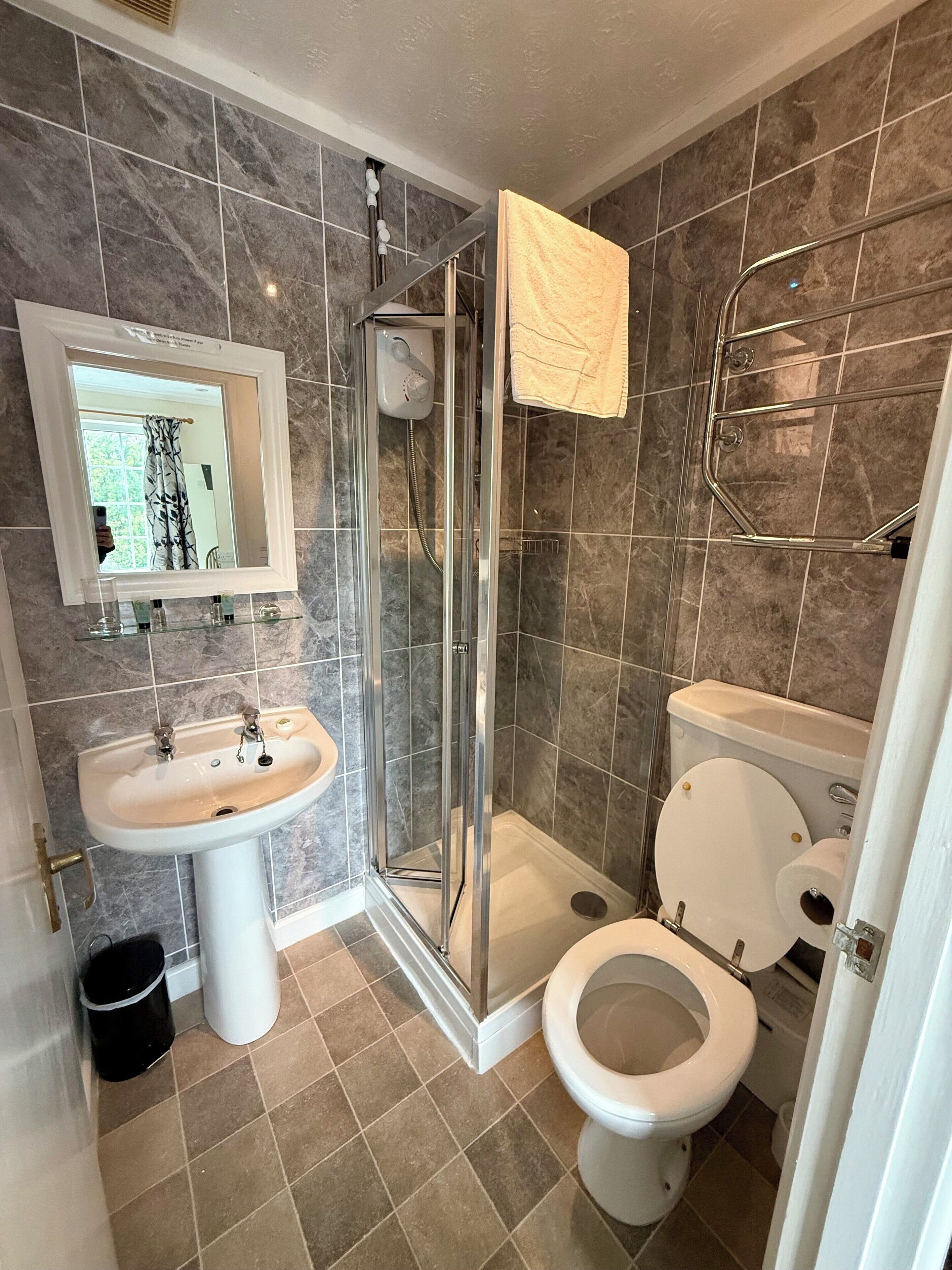 Une salle de bain avec une douche à parois de verre, un lavabo, des toilettes et un miroir.