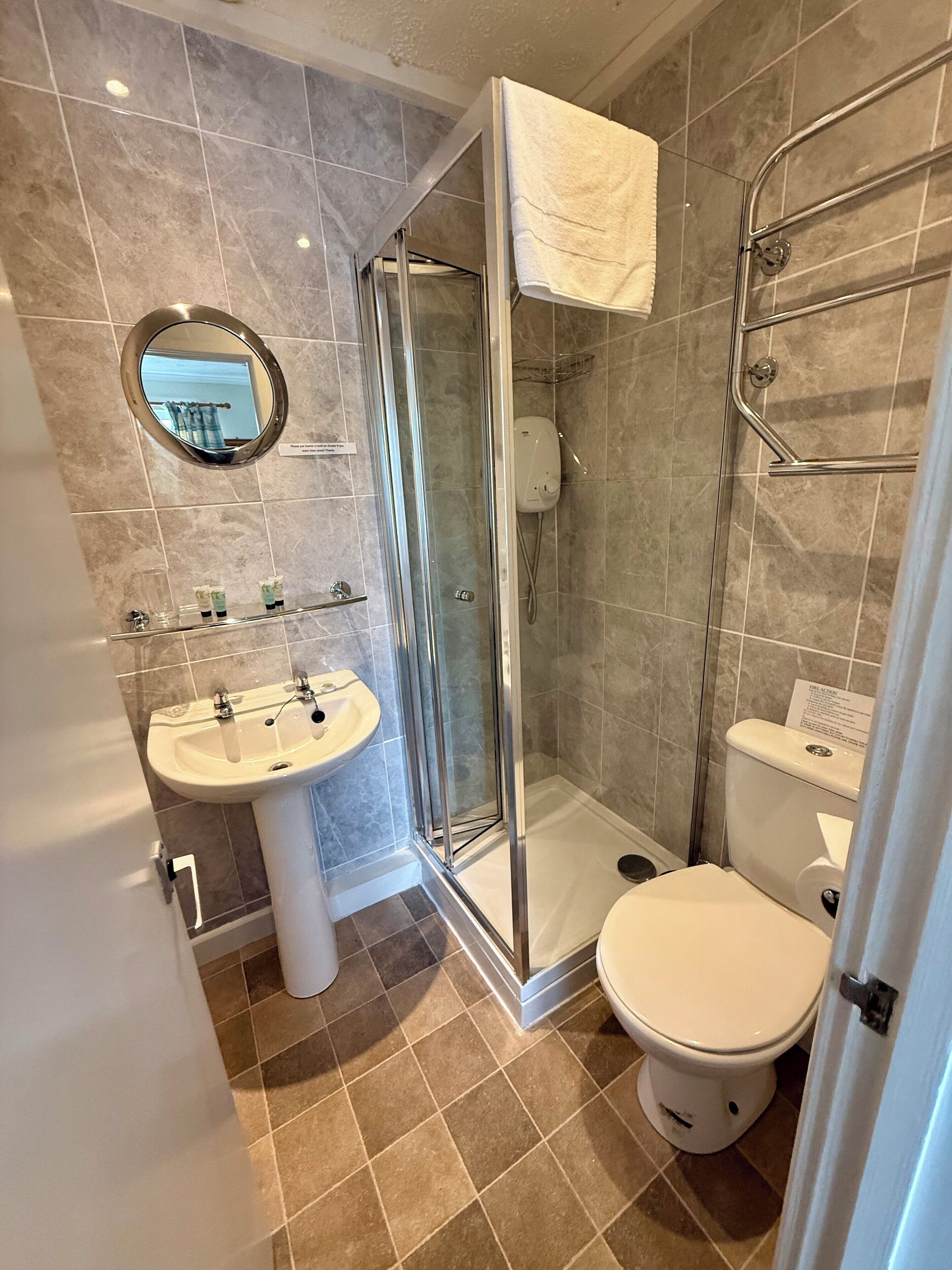 A bathroom with a glass-enclosed shower, a pedestal sink, and a toilet.