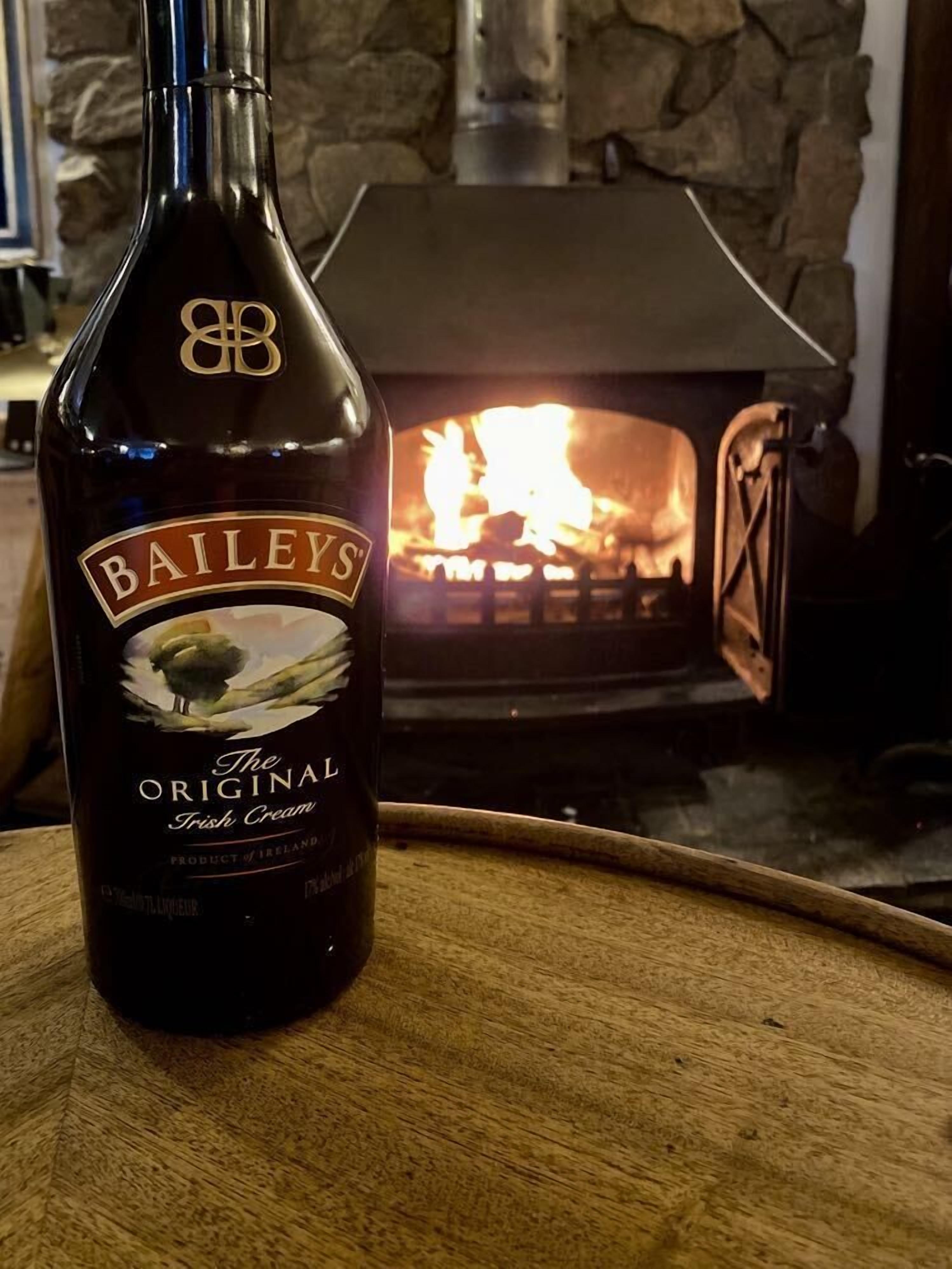 A bottle of Bailey's Original Irish Cream in front of a fireplace.