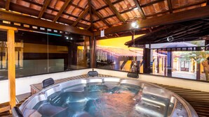 Un jacuzzi con una terraza de madera y vistas a un restaurante y un área de estar al aire libre.