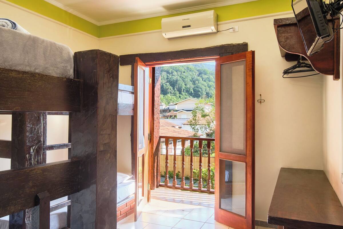 A room with a wooden bench, a tiled floor, a ceiling light, and a view of a balcony with a railing.