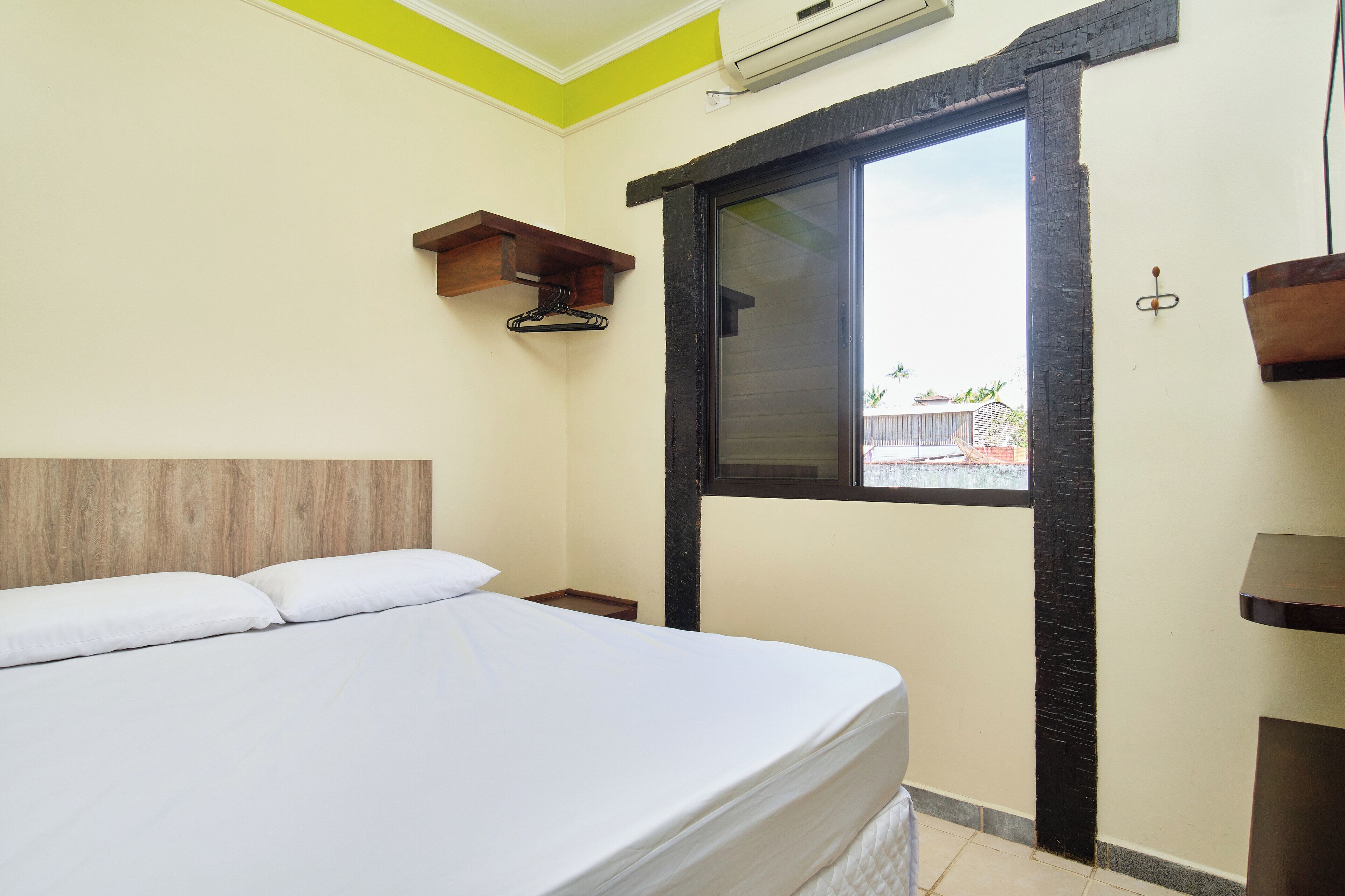 Un dormitorio con cama, ventana y cabecera de madera.