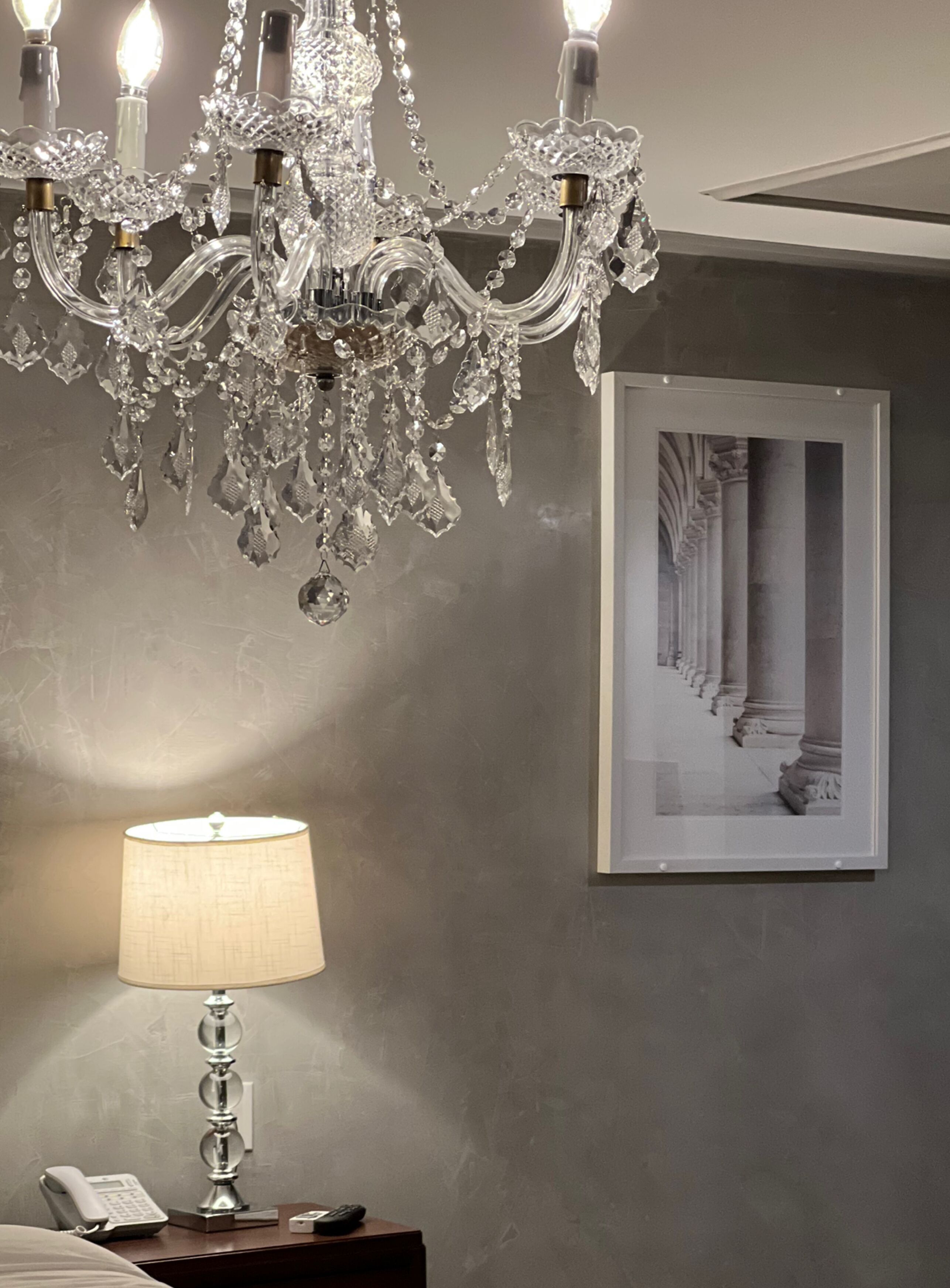 A chandelier, a lamp, and a framed picture on a wall.