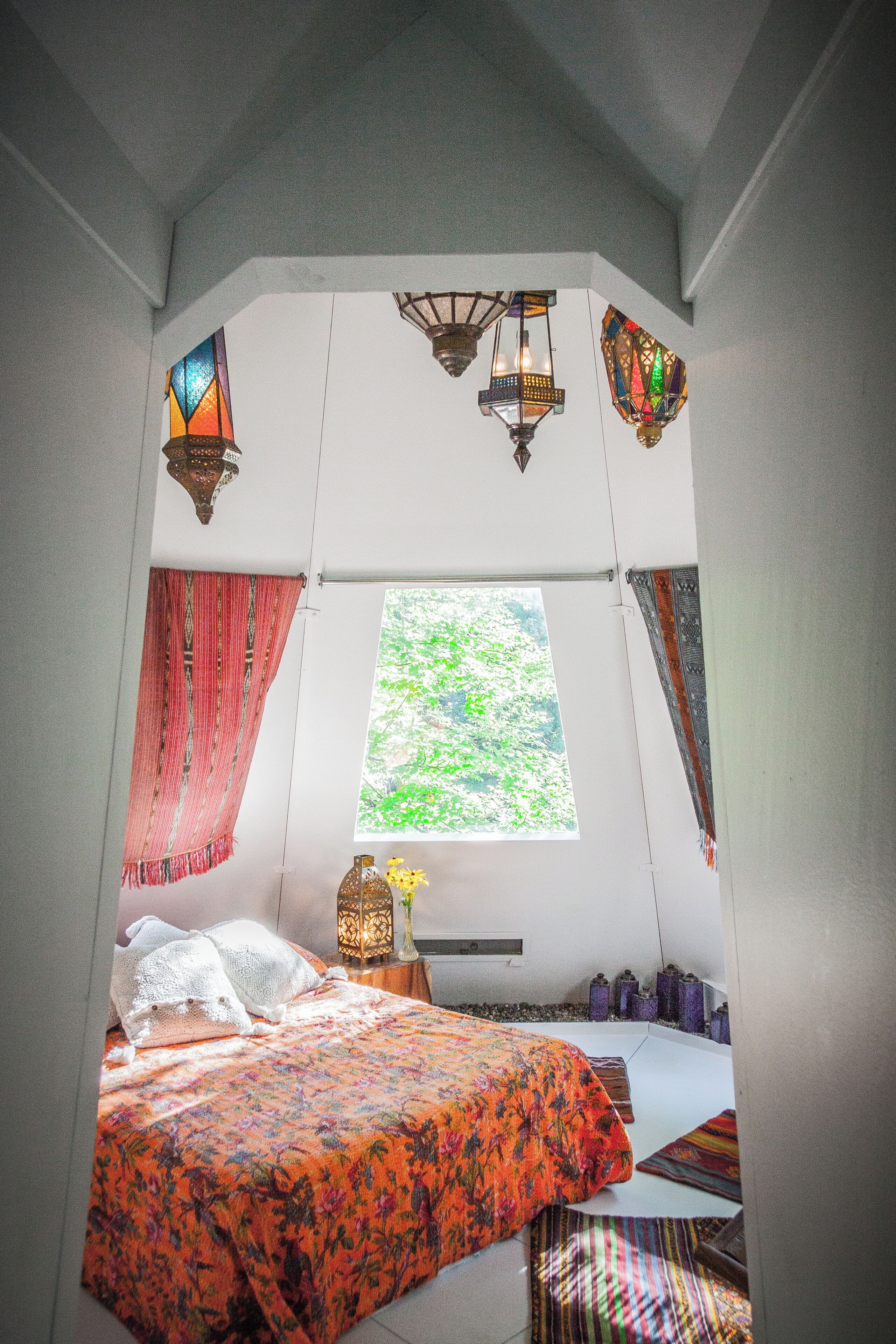 Un dormitorio con cama, ventana y faroles decorativos.