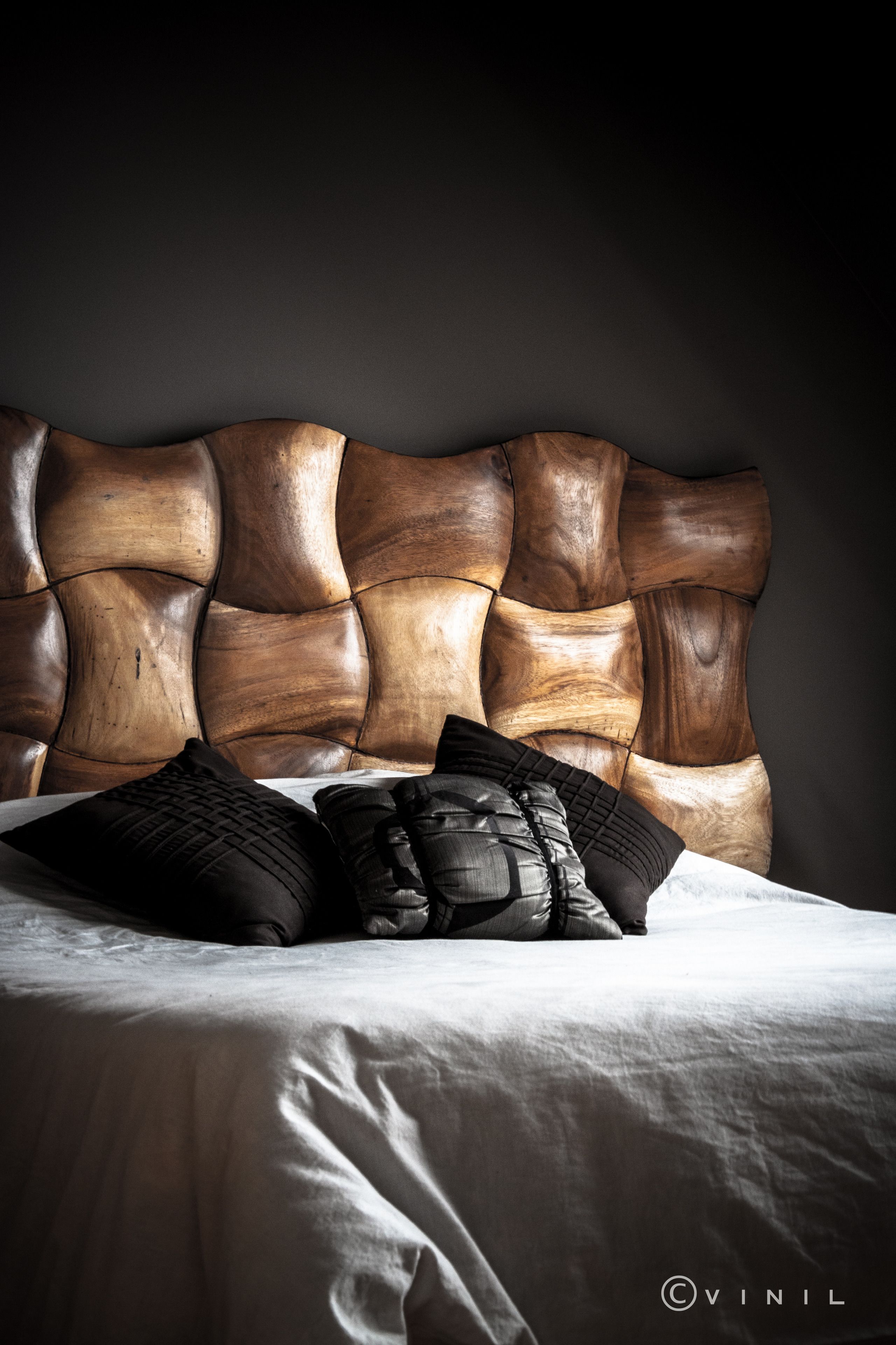 A bed with a wooden headboard and black pillows.