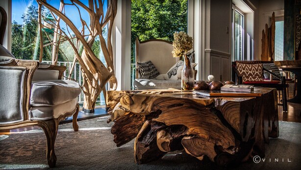 Une pièce avec une grande table en bois, un canapé et une chaise. Il y a une fenêtre donnant sur des arbres.