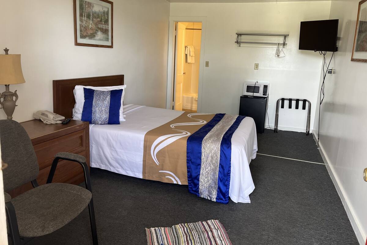Ein Hotelzimmer mit Bett, Schreibtisch mit Telefon, Stuhl, Mikrowelle und Fernseher.