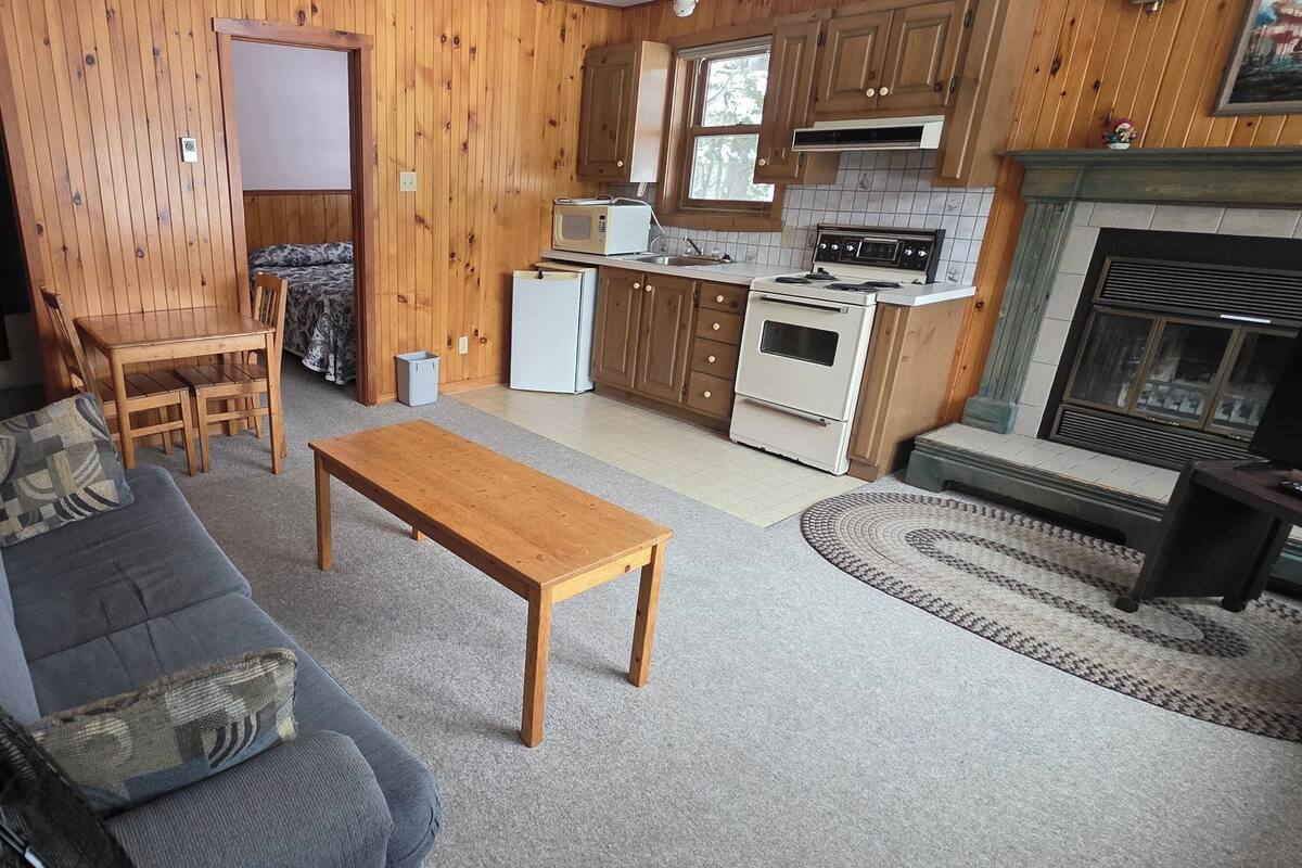 A cozy living room with a sofa, a wooden table, and a fireplace.