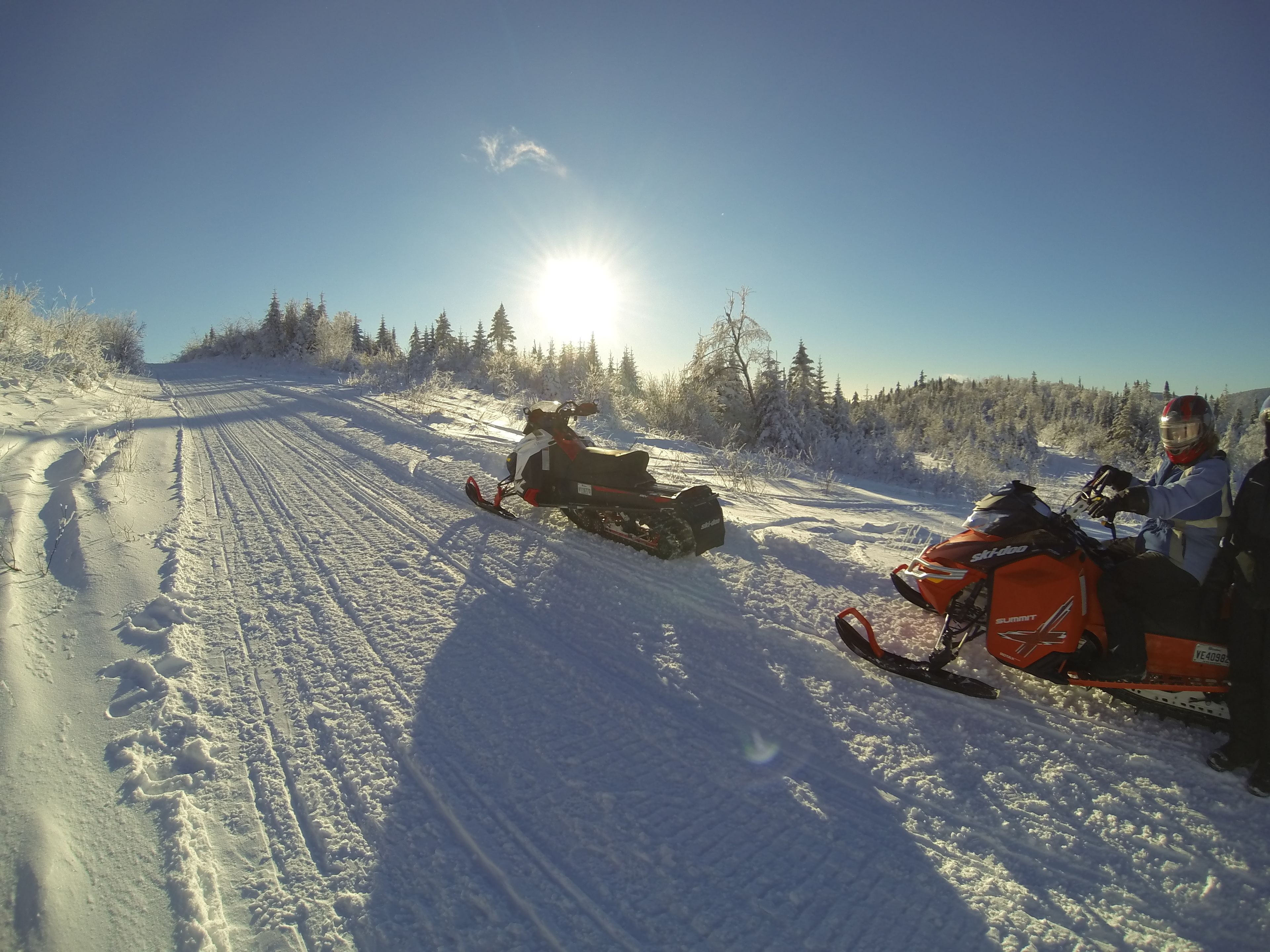Un paisaje nevado con dos motos de nieve en un sendero.