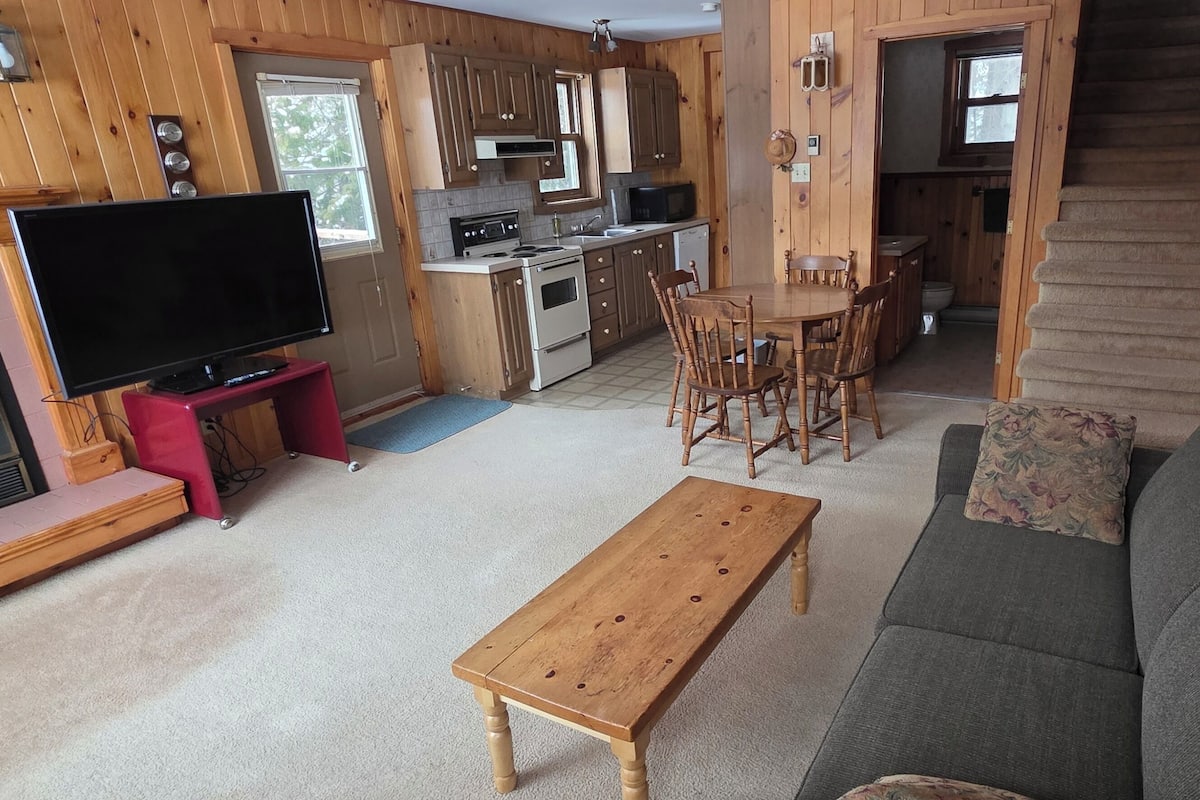 A cozy cabin interior with a living room, a dining area, and a kitchen.