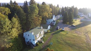 A large house with a green roof, surrounded by trees and a grassy area. - Motel Le Fleuron (Saint Donat)