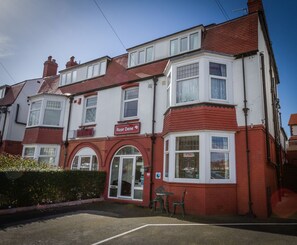A two-story building with a red and white facade, a visible shop sign reading "Rose Dene," and a small outdoor seating area with two chairs. - Rose Dene (Scarborough)