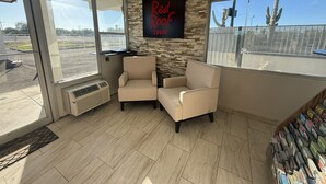 A room with two beige armchairs, a stone wall, and a Red Roof Inn sign. - Red Roof Inn Tucson – Vail (Tucson)