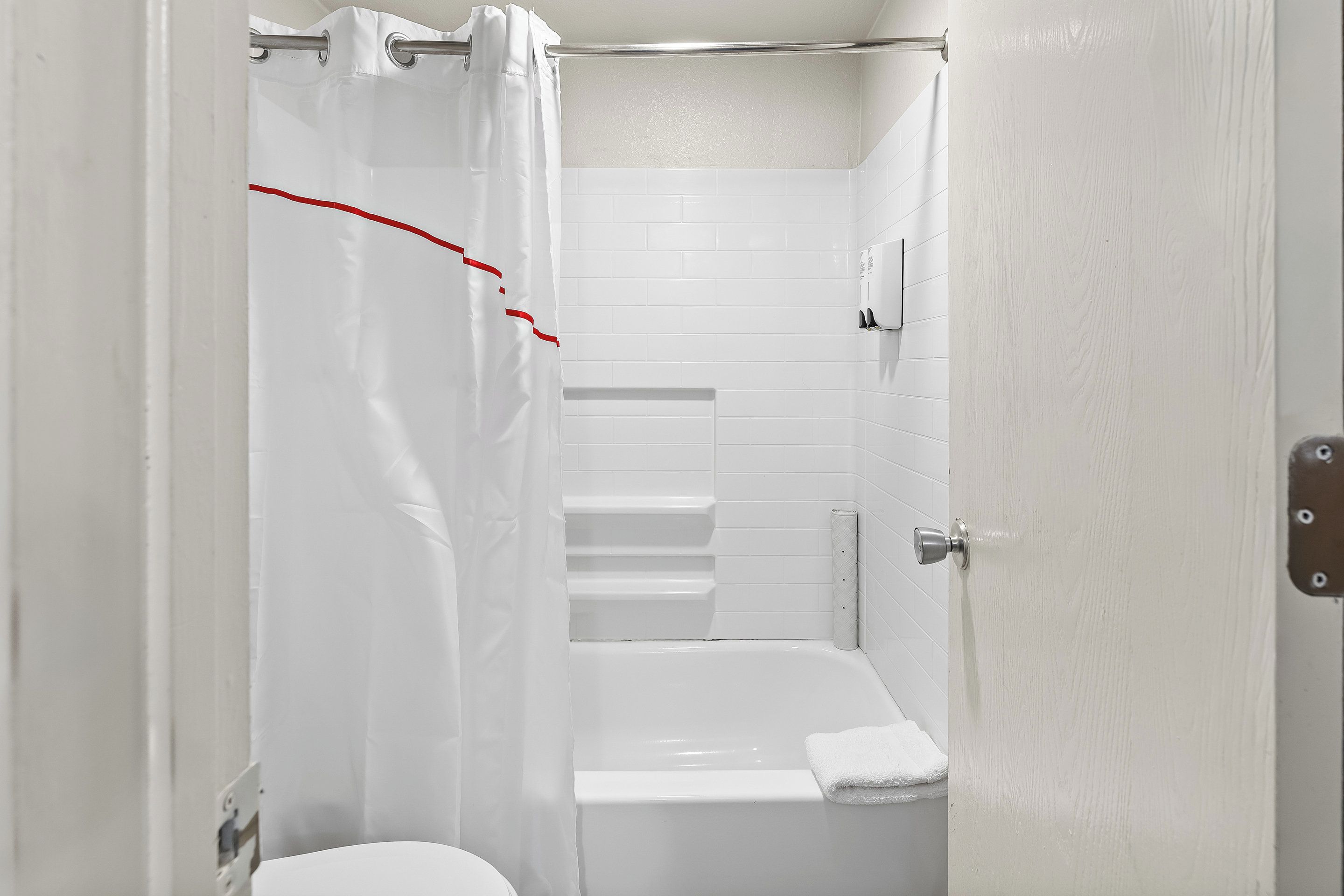 Un baño con una bañera blanca, un inodoro blanco y una cortina de ducha.