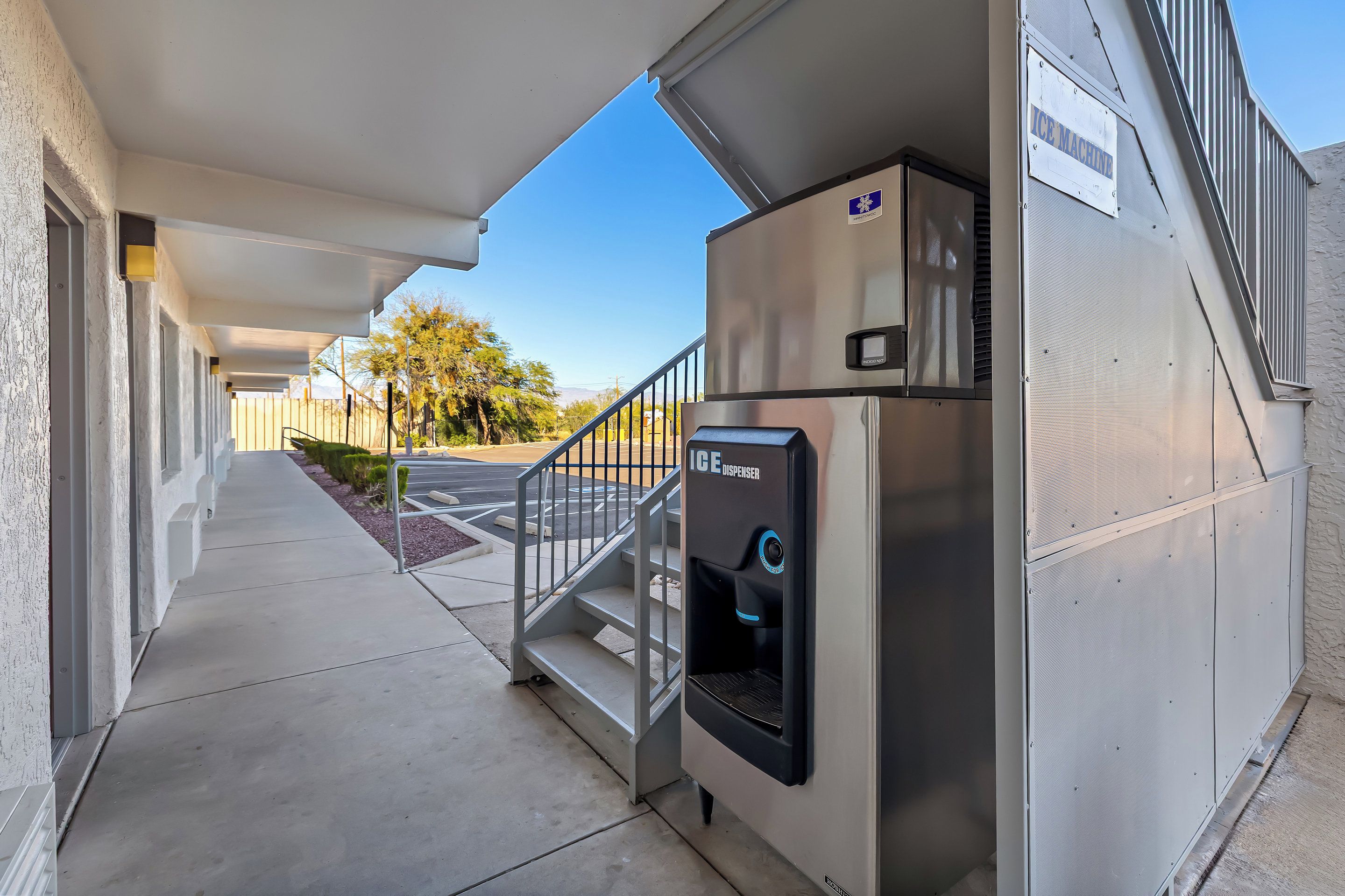 A hallway with a stairway leading to an upper level, a water dispenser, and a sign indicating an ice machine.