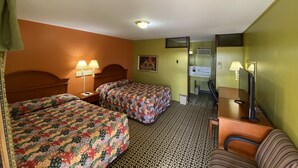 Une chambre d’hôtel avec deux lits, un bureau, une chaise, un miroir et un climatiseur fixé au mur.