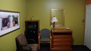 Une chambre d’hôtel équipée d’un lit, d’un bureau avec une lampe, d’une chaise, d’un réfrigérateur et d’un téléviseur fixé au mur.