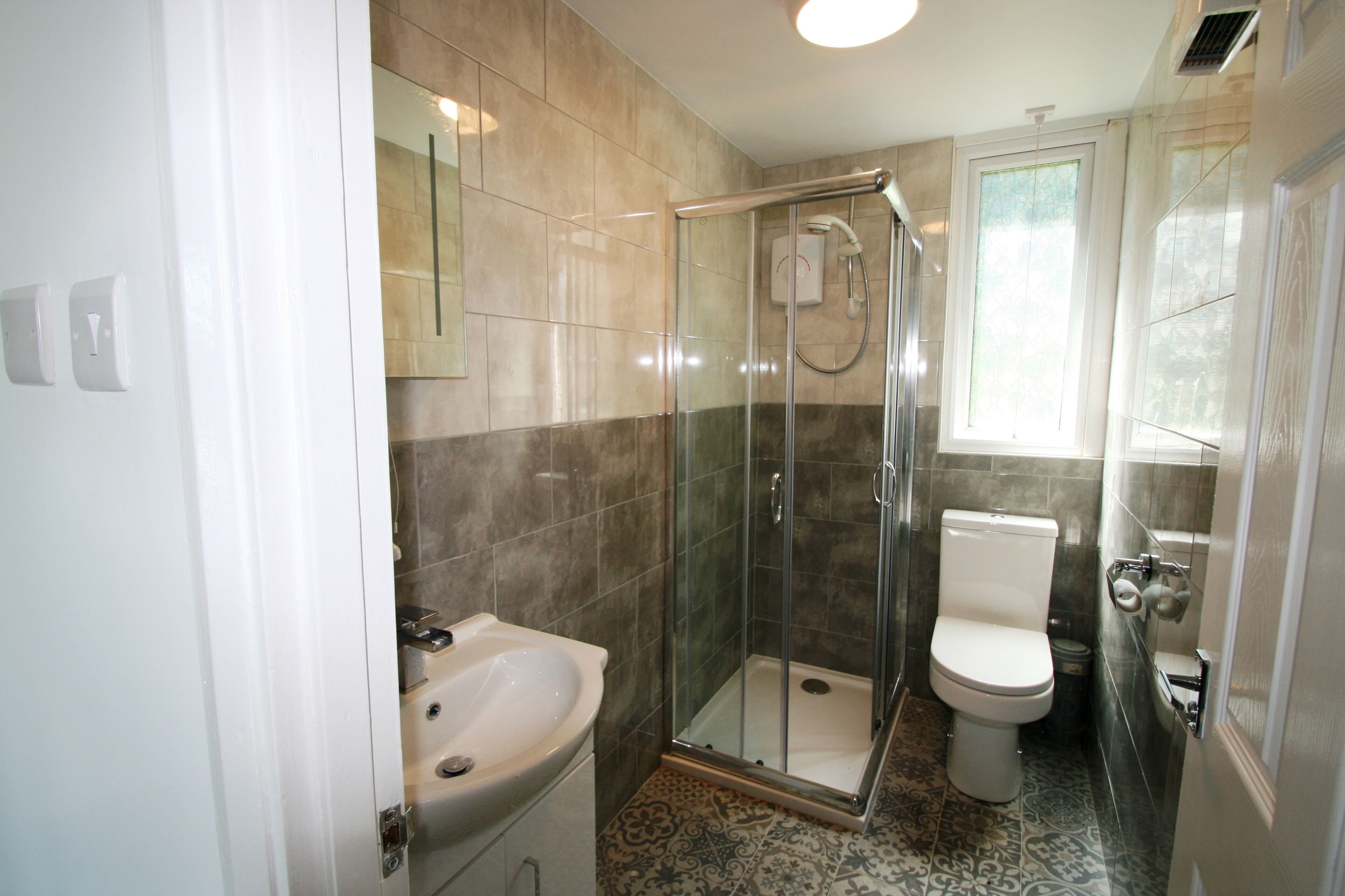 A bathroom with a glass-enclosed shower, a toilet, and a sink.